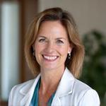 Portret Dr Anny Kowalskiej, uśmiechniętej kobiety w średnim wieku na zielonym tle