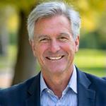 Portret Prof. Jana Wiśniewskiego, energicznego, starszego, siwego mężczyzny na szarym tle